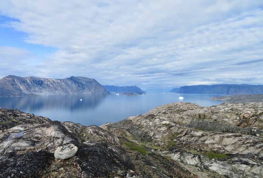 Blick von einem Felsgipfel über die weite Bucht von Uummannaq mit einzelnen Eisbergen