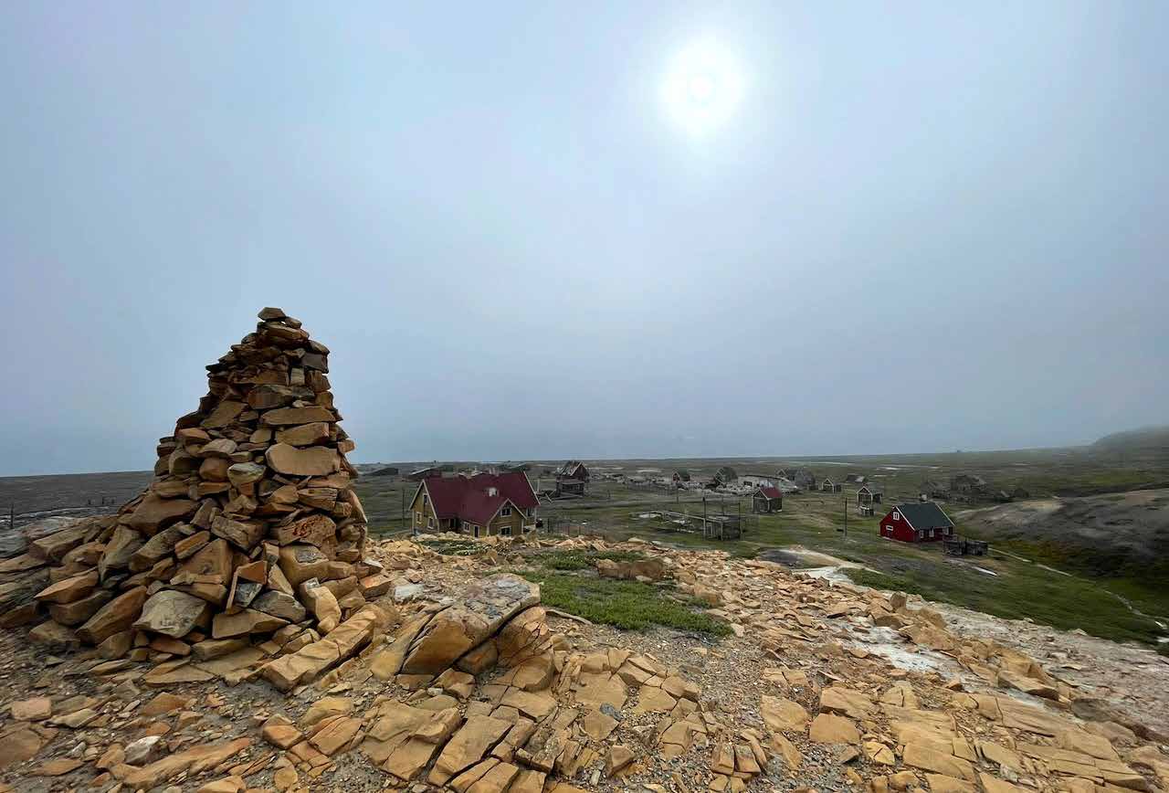 Steinmann auf einem Felsrücken über der verlassenen Bergbausiedlung Qullissat im Nebel